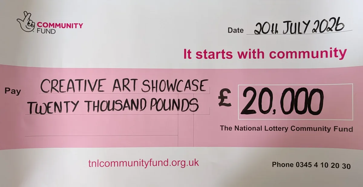 A large presentation cheque from The National Lottery Community Fund, dated 20 July 2026, made out to Creative Art Showcase for twenty thousand pounds, £20,000